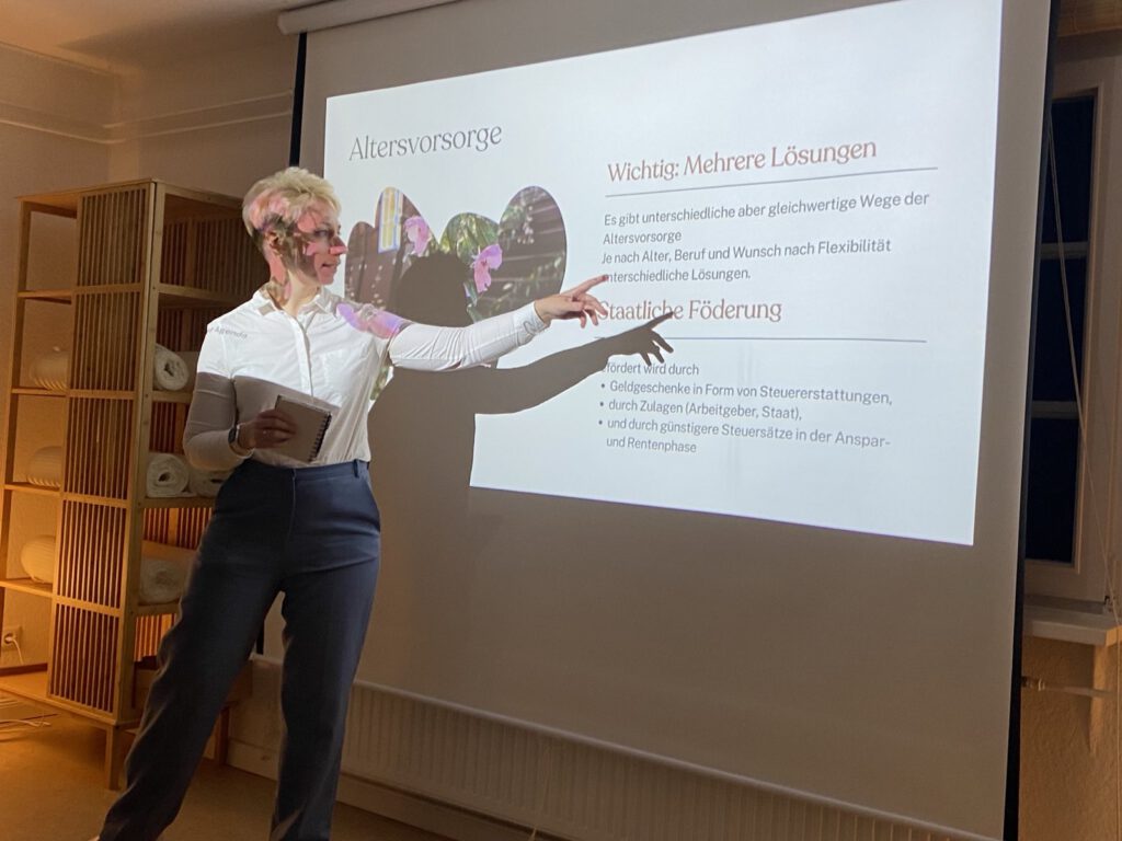 Referentin und Investment-Coachin Ursula Stieler deutet auf eine Workshop-folie, die Investment für die Altersvorsorge zeigt.